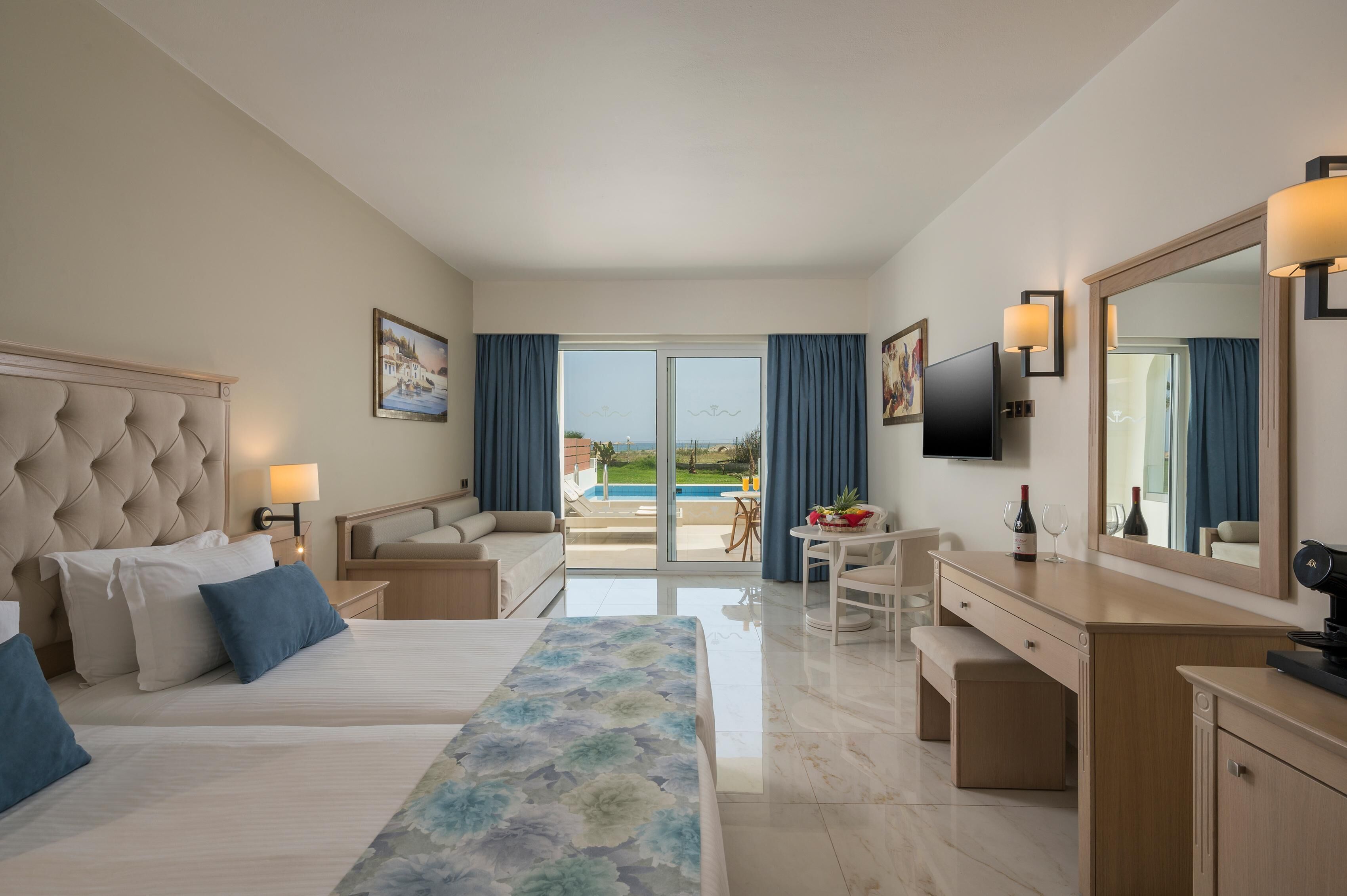 Habitación de hotel con cama, escritorio, silla, televisión y vista a la piscina.