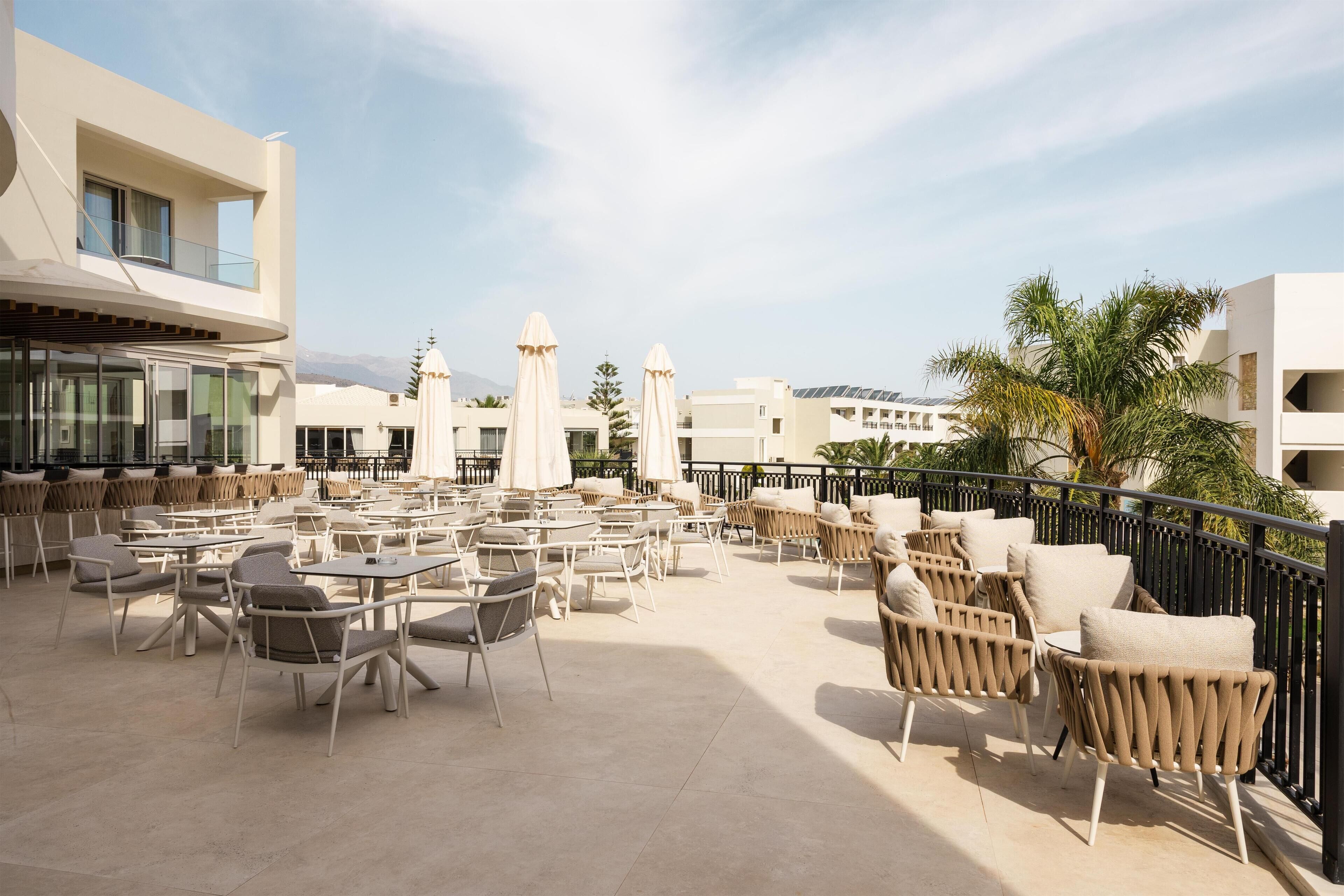 A rooftop terrace with outdoor seating, including tables and chairs, and umbrellas.