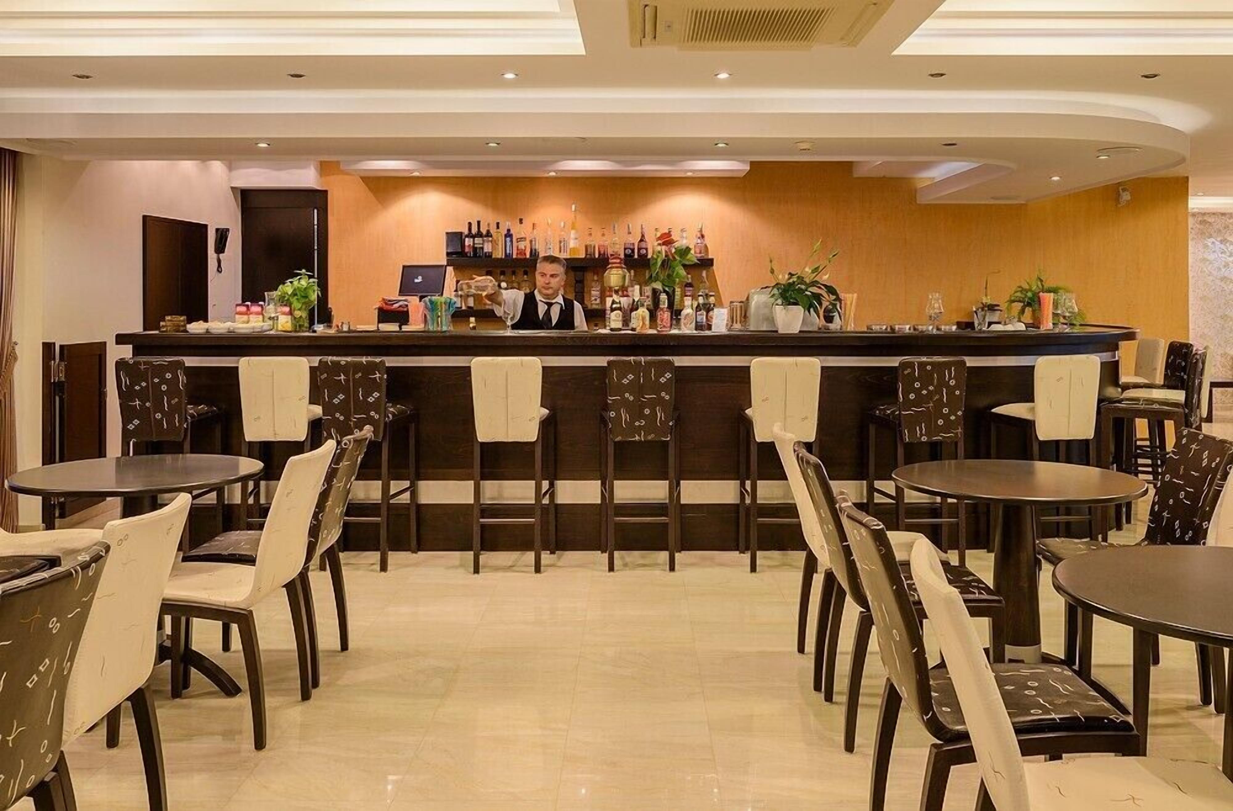 A bar area with a bartender, multiple tables, and chairs.