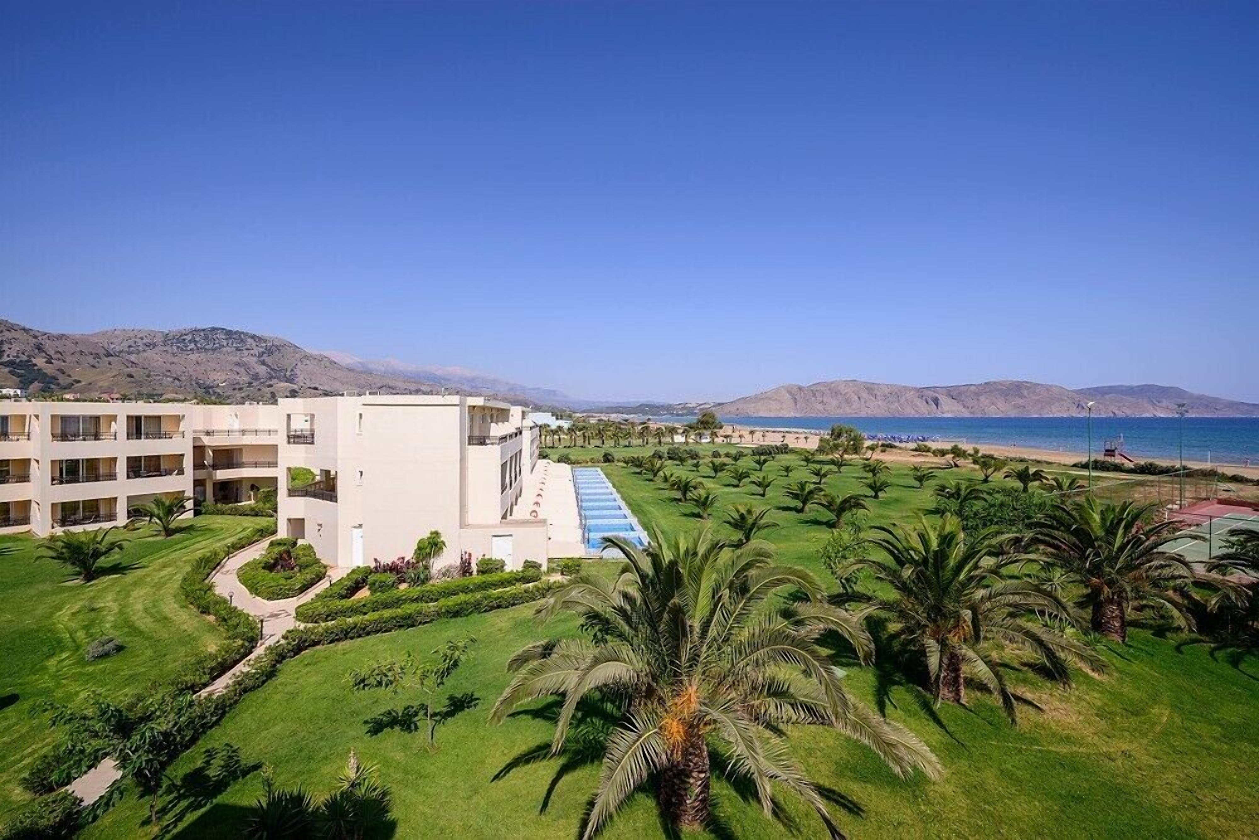 Un resort con piscina, palmeras y vista al mar.