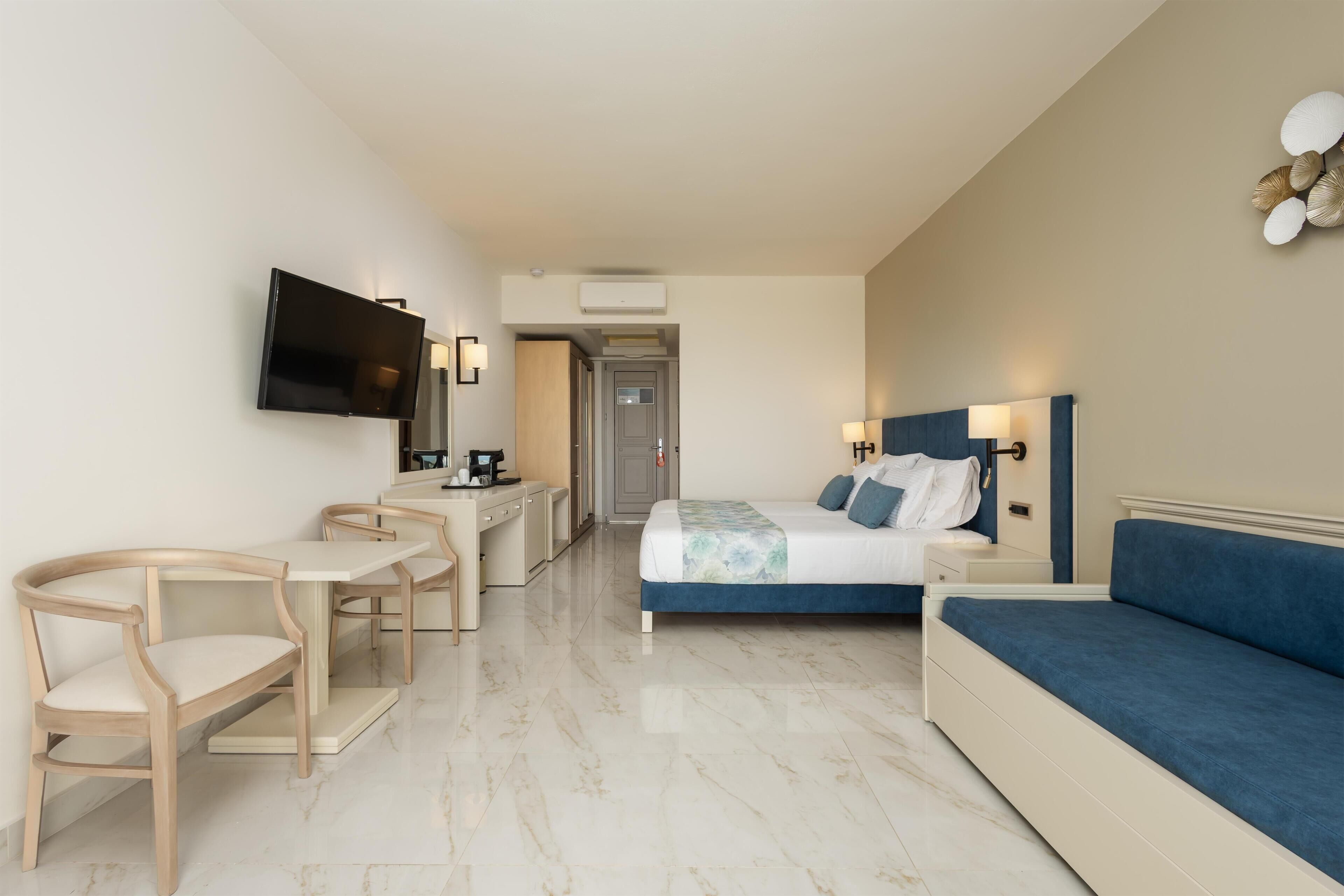 Una habitación de hotel con una cama, un escritorio, una silla, un televisor y un sofá.
