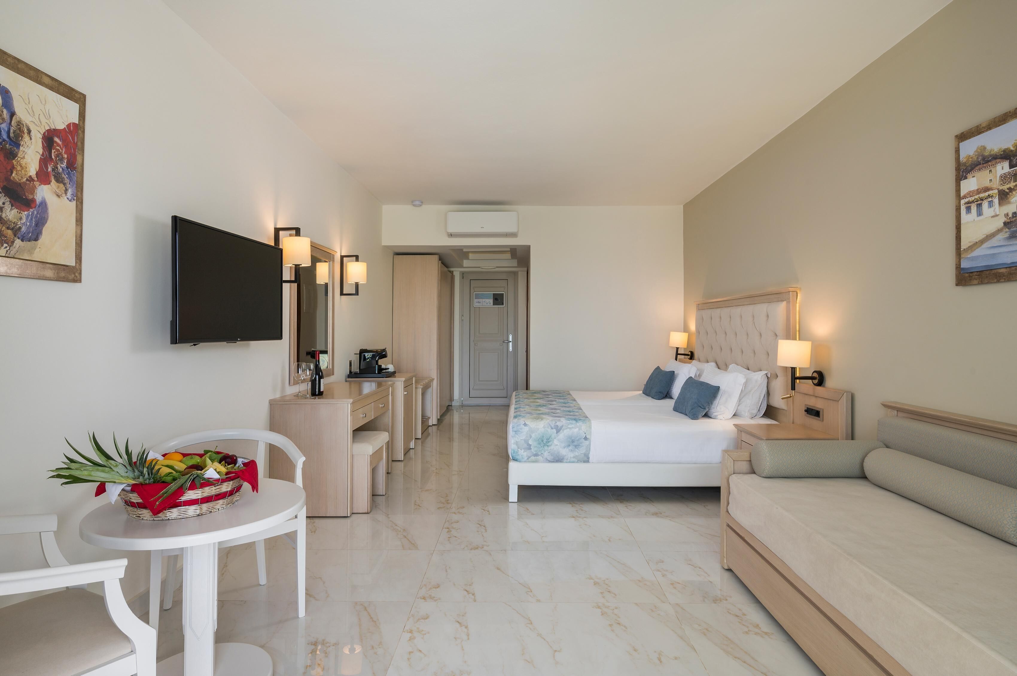 Ein Hotelzimmer mit Bett, Sofa, Schreibtisch und Fernseher.