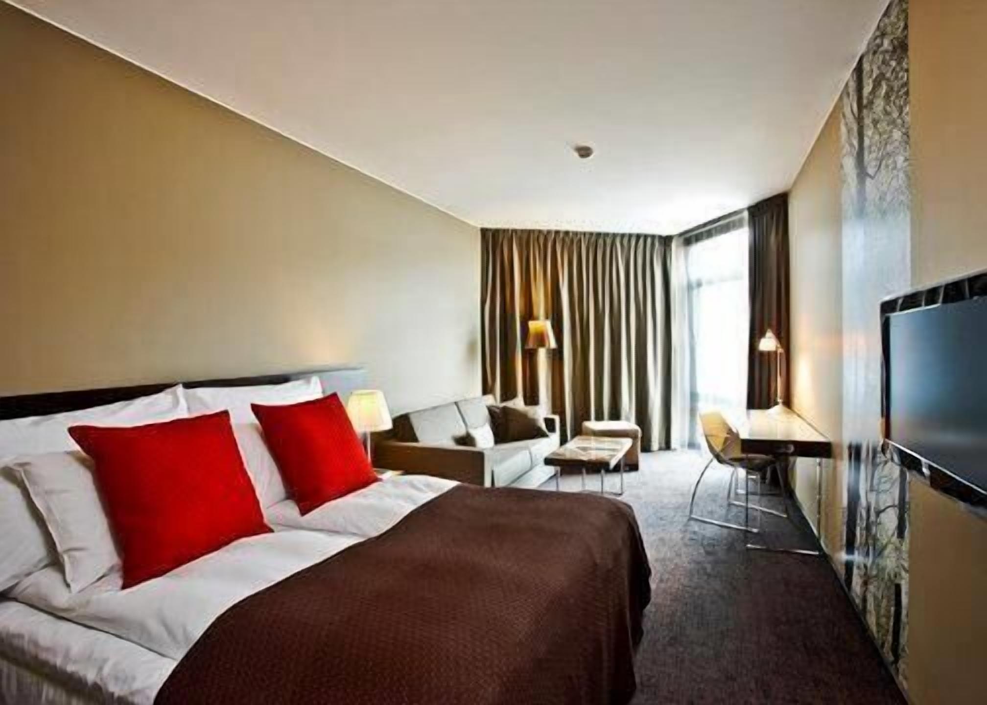 Habitación de hotel con cama, sofá, escritorio y televisor.