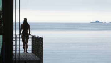 A person standing on a balcony overlooking a calm sea.