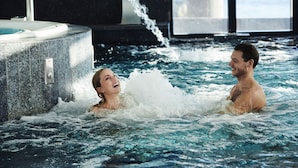 A couple in a hot tub with water jets, surrounded by a modern interior with large windows. - Farris Bad (Larvik)