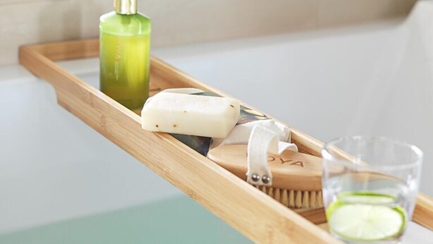 A wooden tray with a green bottle, a bar of soap, a brush, and a glass with a lime slice. - Farris Bad (Larvik)