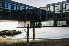 Un bâtiment moderne à la façade vitrée, donnant sur une étendue d’eau.