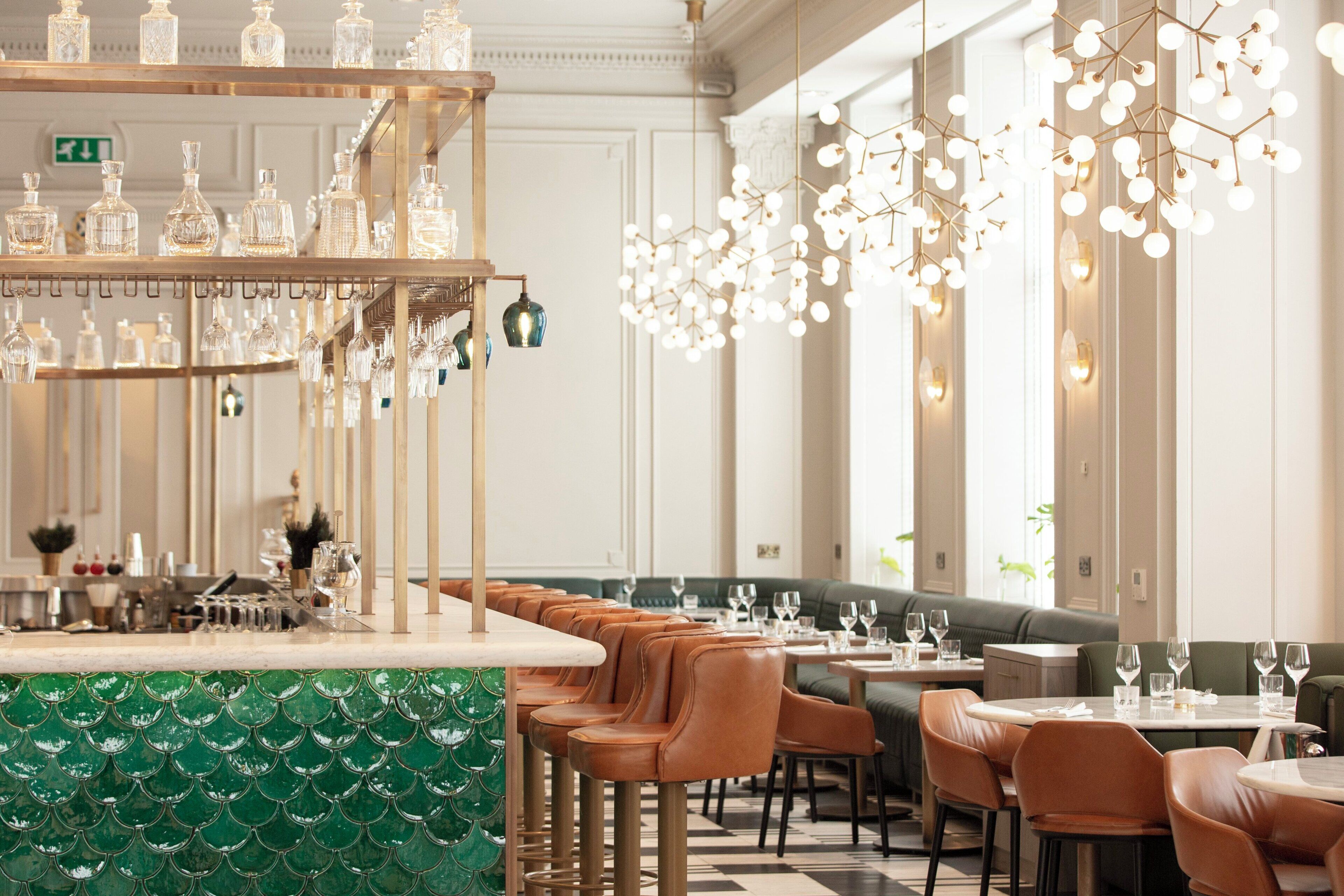A bar area with a green patterned countertop, leather bar stools, and hanging light fixtures.