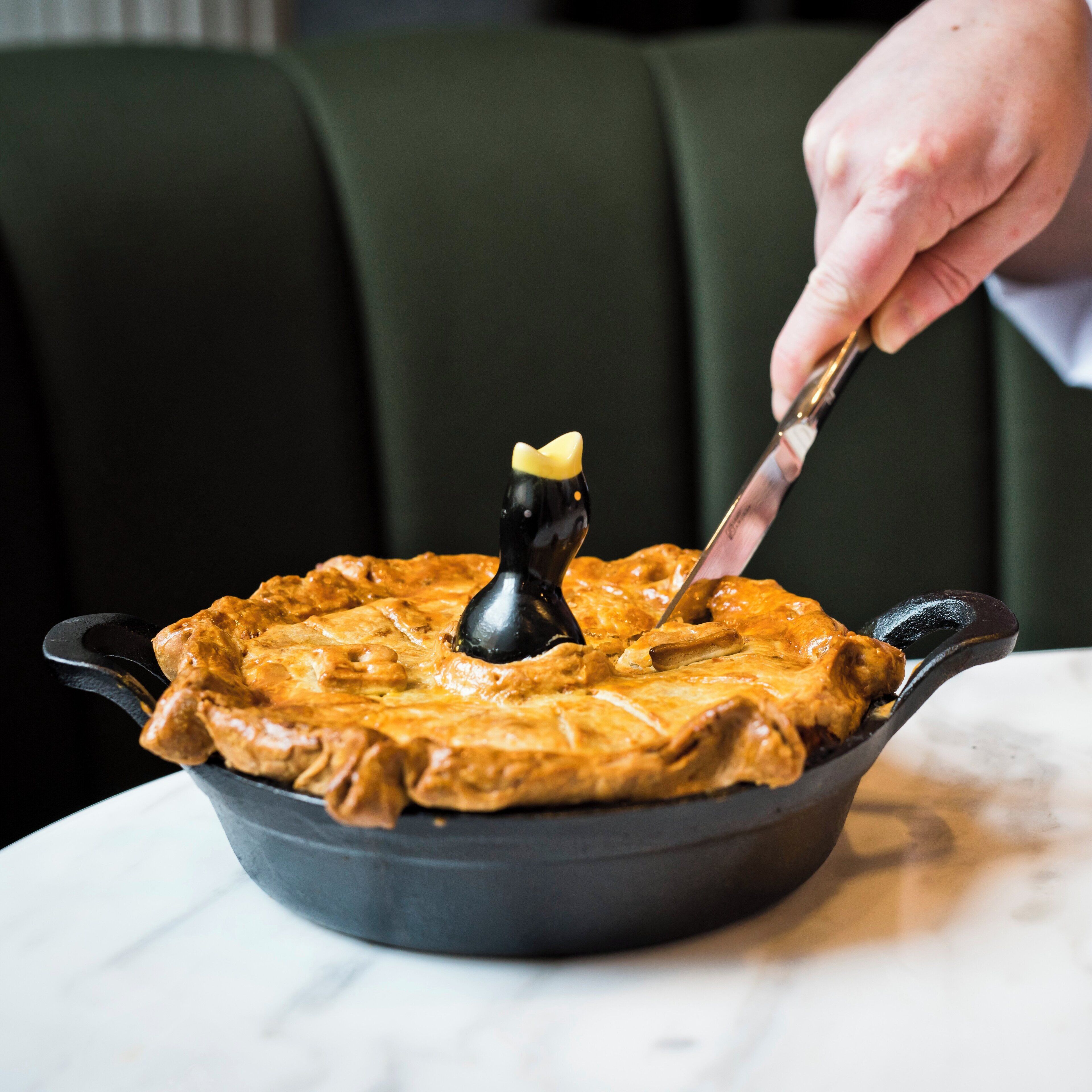 A person serving a pie in a cast iron skillet.