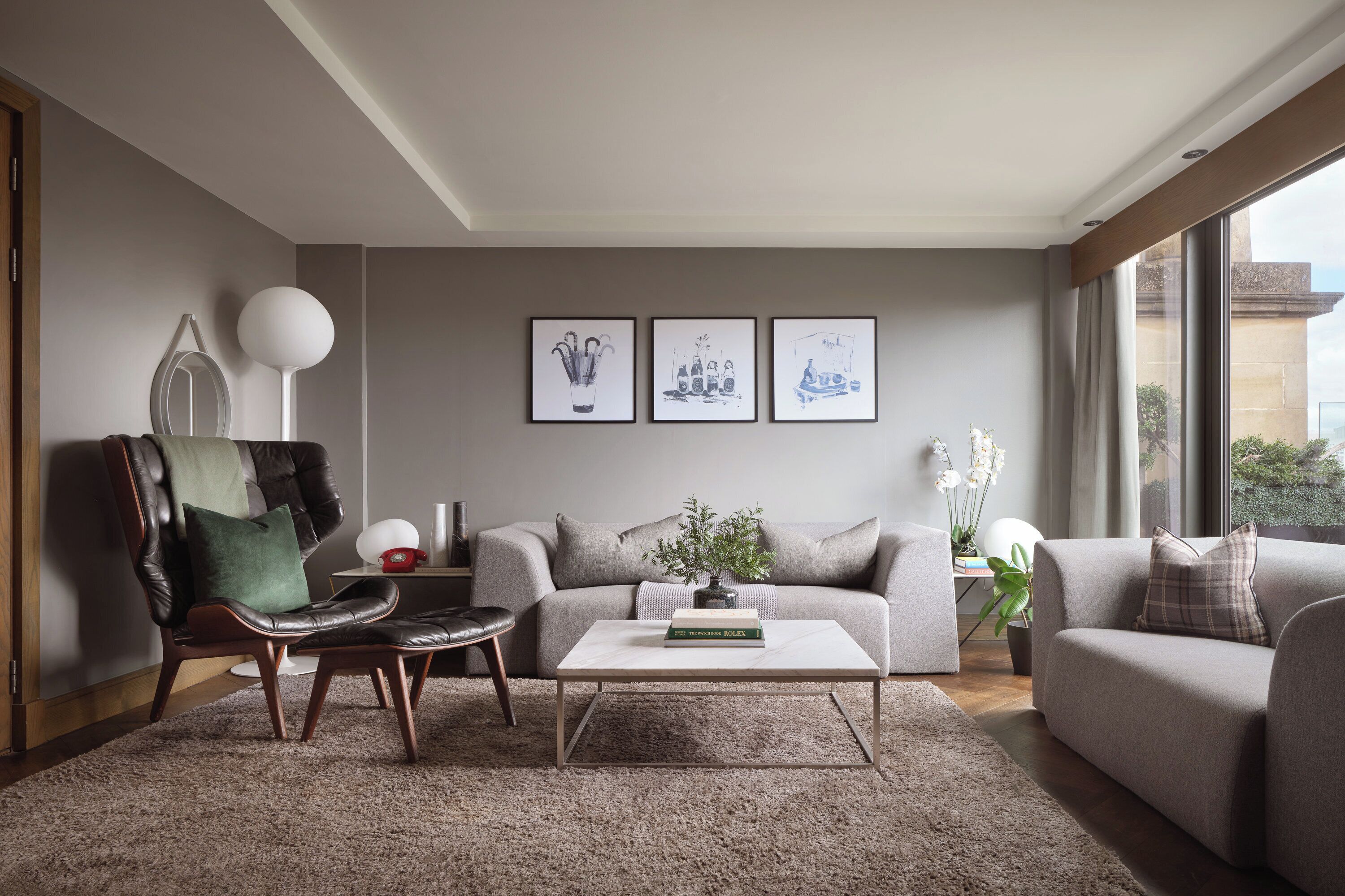 Ein modernes Wohnzimmer mit Sofa, Sessel, Couchtisch und Kunstwerk an der Wand.
