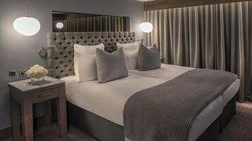 Una habitación de hotel con una cama grande, dos mesitas de noche, un espejo y una ventana con cortinas.