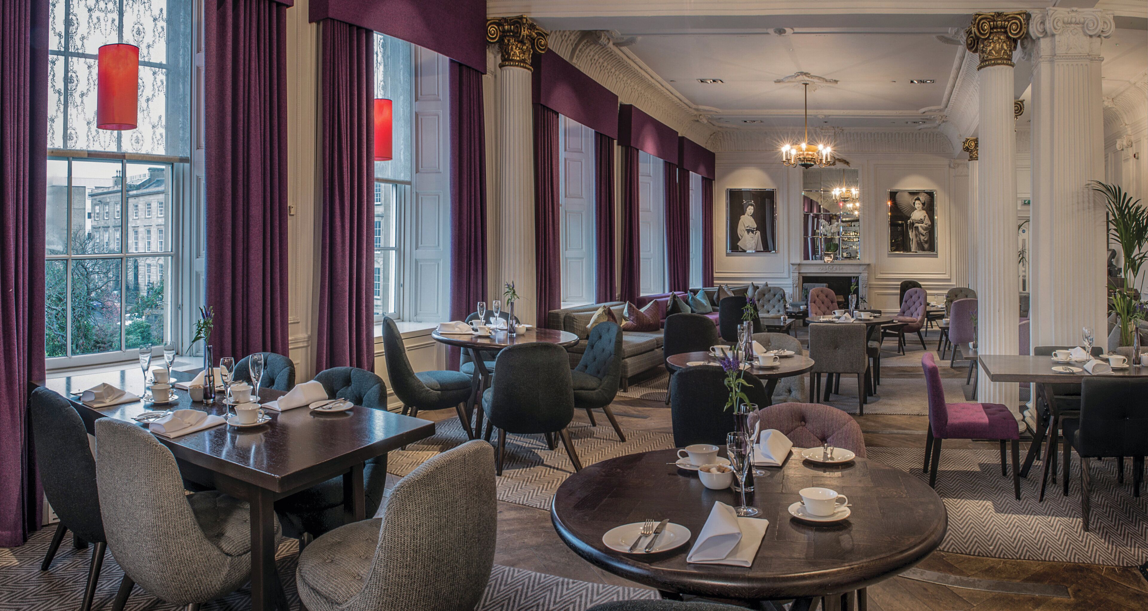 A hotel dining area with multiple tables, chairs, and a fireplace.