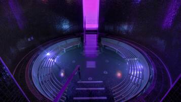 A circular auditorium with a central stage and a purple light at the back.