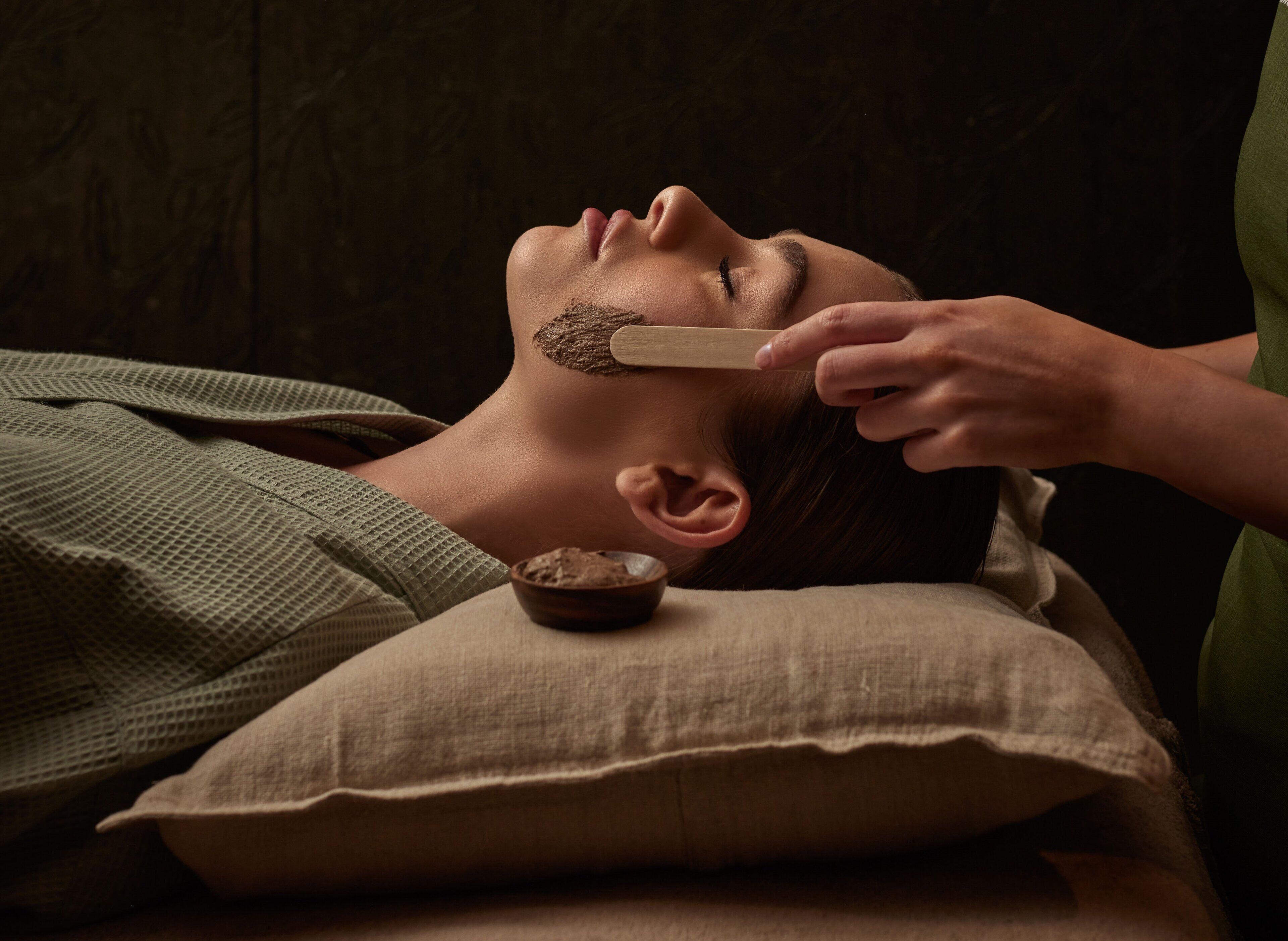 A person lying down with a bowl of brown substance on a pillow.