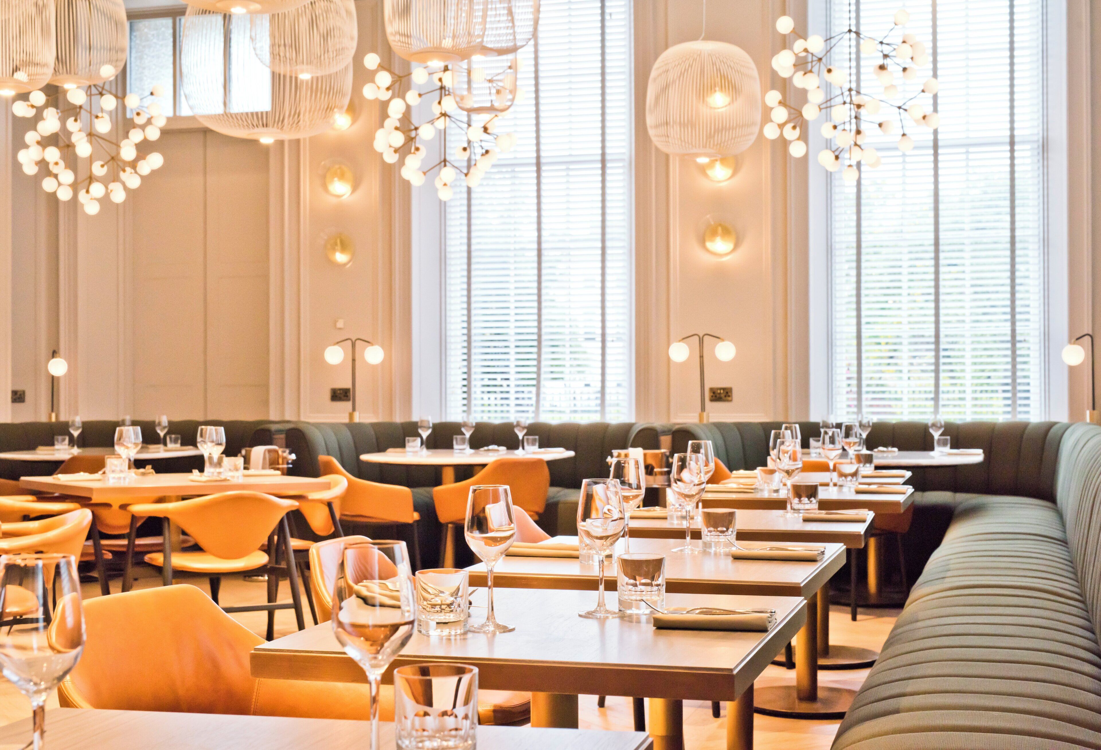 A restaurant interior with multiple dining tables, chairs, and a variety of lighting fixtures.