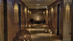 A hallway with wooden paneling, hanging lamps, and a seating area with a table and chairs. - Kimpton Blythswood Hotel & Spa by IHG (Glasgow)