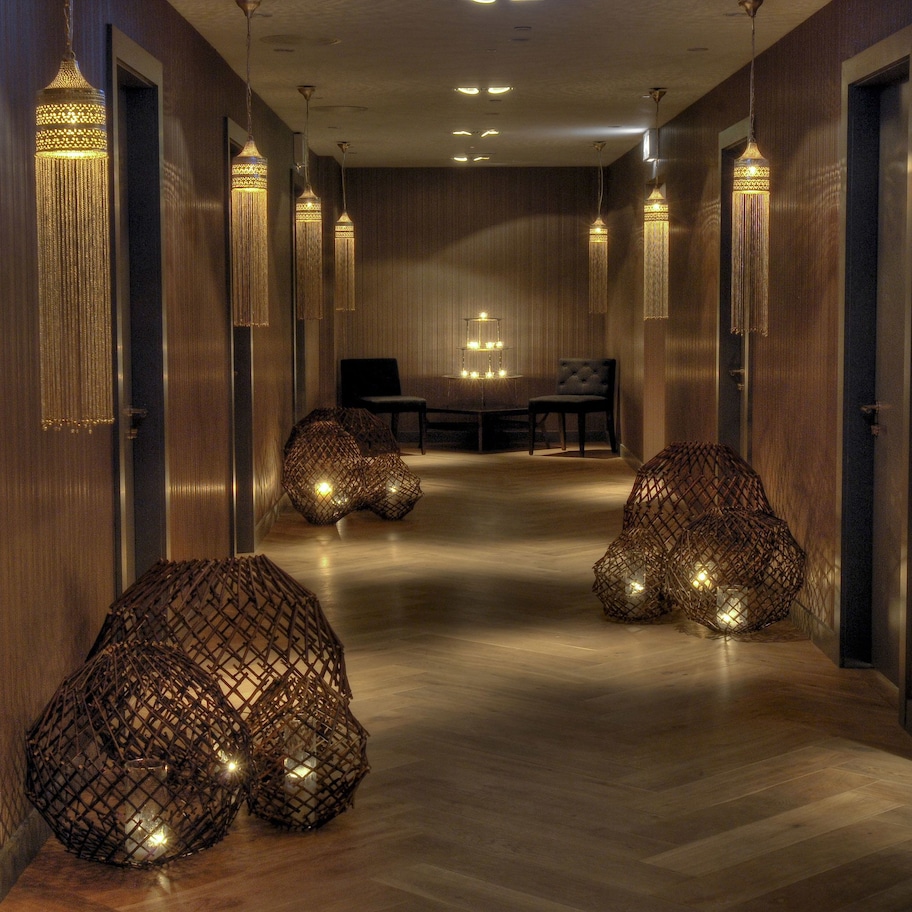 A hallway with wooden paneling, hanging lamps, and a seating area with a table and chairs.