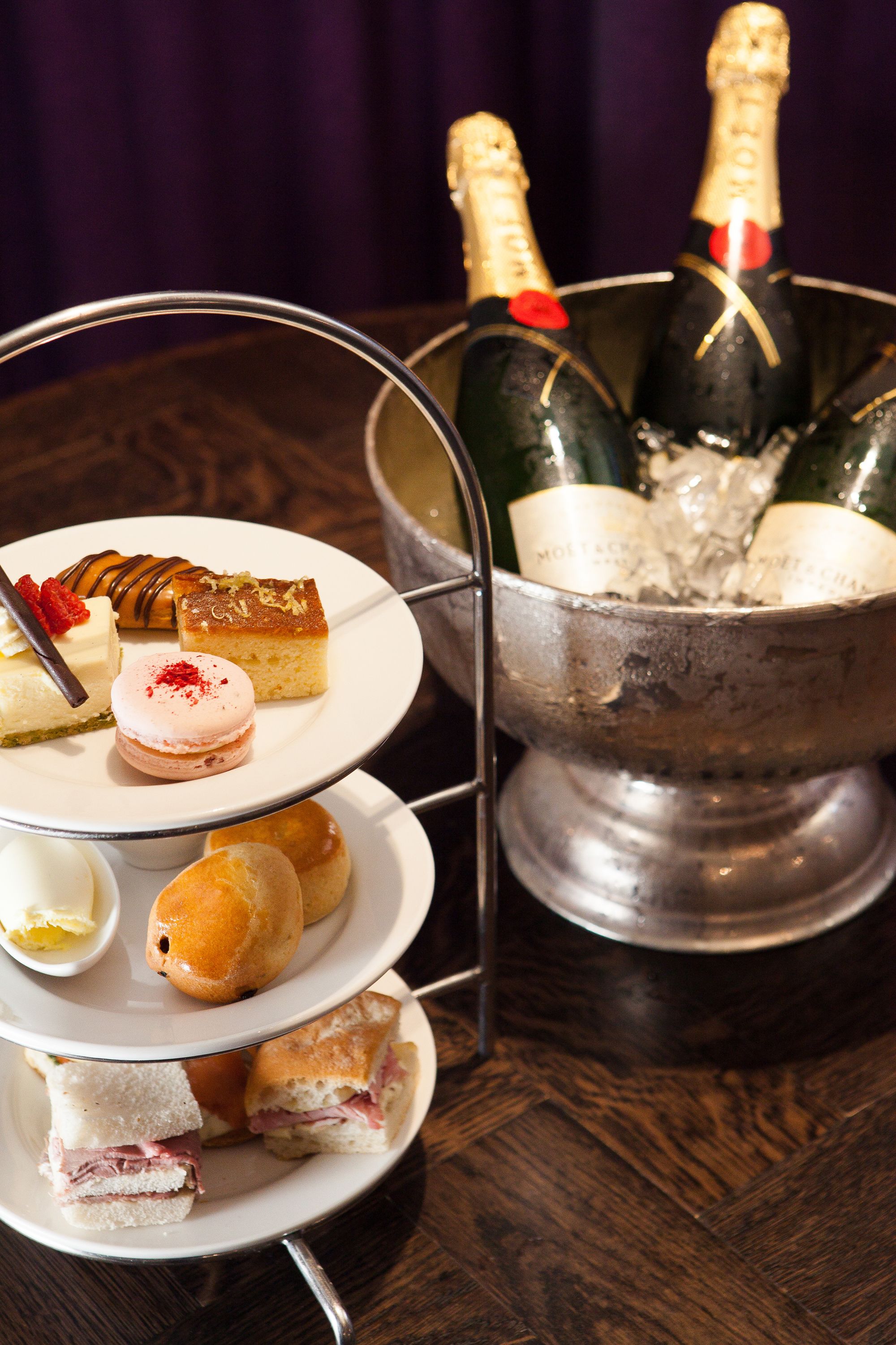 A dessert tray with various pastries and a champagne bucket with bottles.