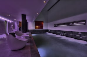 A modern spa area with a large hot tub, seating, and a sleek design.