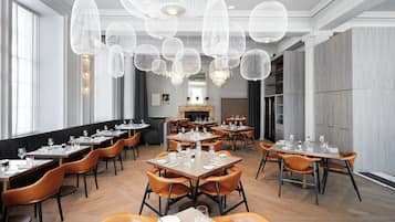 Un restaurante con varias mesas, sillas y una araña con lámparas esféricas.