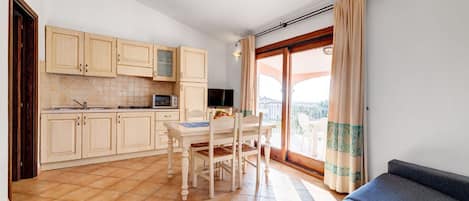 Una cucina compatta con tavolo e sedie, un divano e un'ampia finestra con tende.