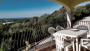 A balcony with a table and chairs, overlooking a scenic landscape.