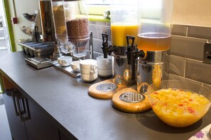 Eine Küchenarbeitsplatte mit Kaffeemaschinen, einer Kaffeemühle, einer Obstschale und einem Kaffeeautomaten.