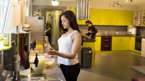 Une cuisine moderne avec des armoires jaunes, des appareils en acier inoxydable et une personne qui prépare des aliments.