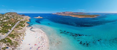 Perto da praia, areia branca, guarda-sóis 