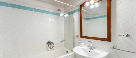 A bathroom with a bathtub, a sink, and a mirror.