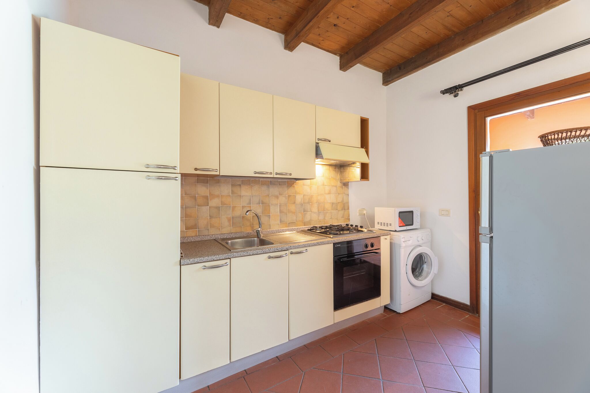 A compact kitchen with a sink, stove, oven, microwave, and washing machine.