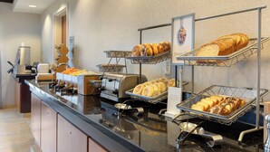 Um buffet de café da manhã com diversos pães e doces.