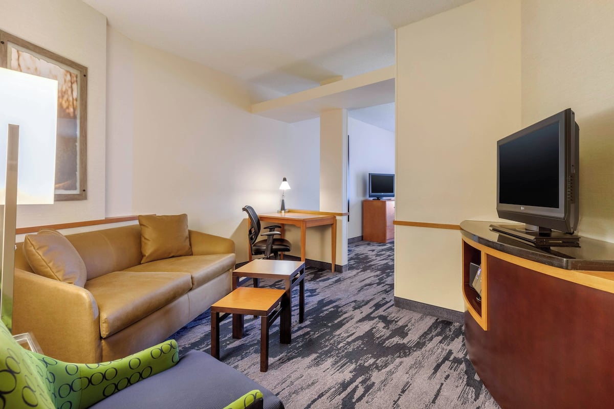 Una habitación de hotel con sofá, escritorio, televisión y lámpara.