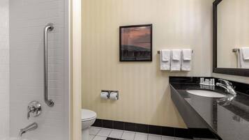 A modern bathroom with a bathtub, a sink, and a toilet. There is a handrail in the shower area, a framed picture on the wall, and a checkered floor pattern.