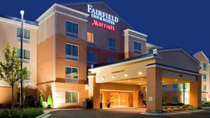 Um hotel Fairfield Inn & Suites Marriott com entrada acessível, estacionamento e fachada bem iluminada.