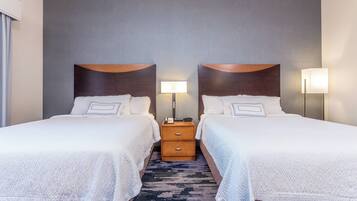 A hotel room with two beds, a nightstand with a lamp, and a patterned carpet.
