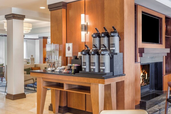 Un espace dédié au café, équipé de plusieurs distributeurs de café, agrémenté d’une œuvre d’art encadrée et d’une cheminée en arrière-plan.