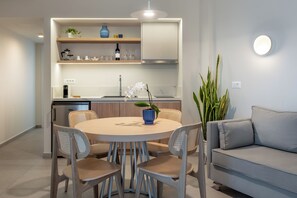 Eine moderne Küche mit integrierten Geräten, eine Essecke mit rundem Tisch und Stühlen sowie ein Wohnbereich mit einer Couch.
