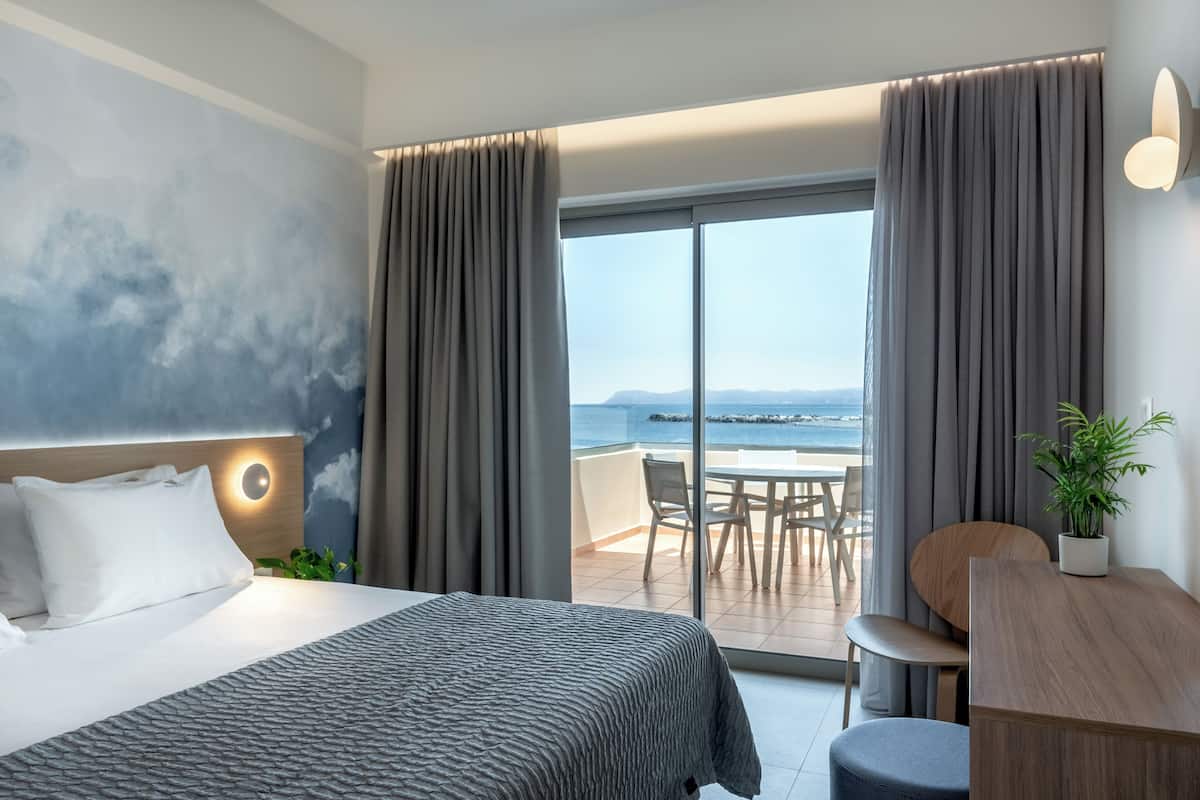 Habitación de hotel con cama, escritorio, silla y vista al océano.
