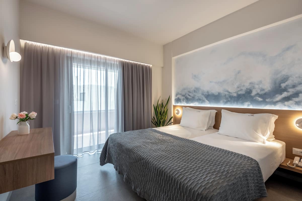 Una habitación de hotel con una cama grande, un escritorio, una silla, una planta y un mural de gran tamaño.