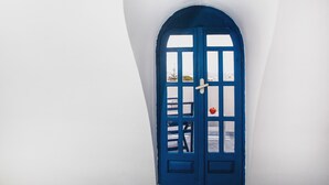 Une porte bleue, un mur blanc et une fenêtre.