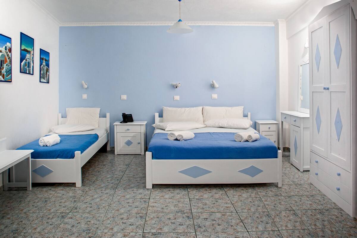 A bedroom with two beds, a nightstand, a dresser, and a ceiling light.