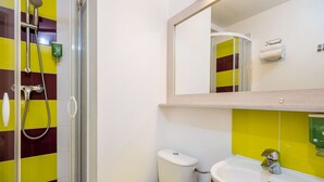 A bathroom with a shower, toilet, sink, and a mirror. - Comfort Hotel Orleans Olivet (Olivet)