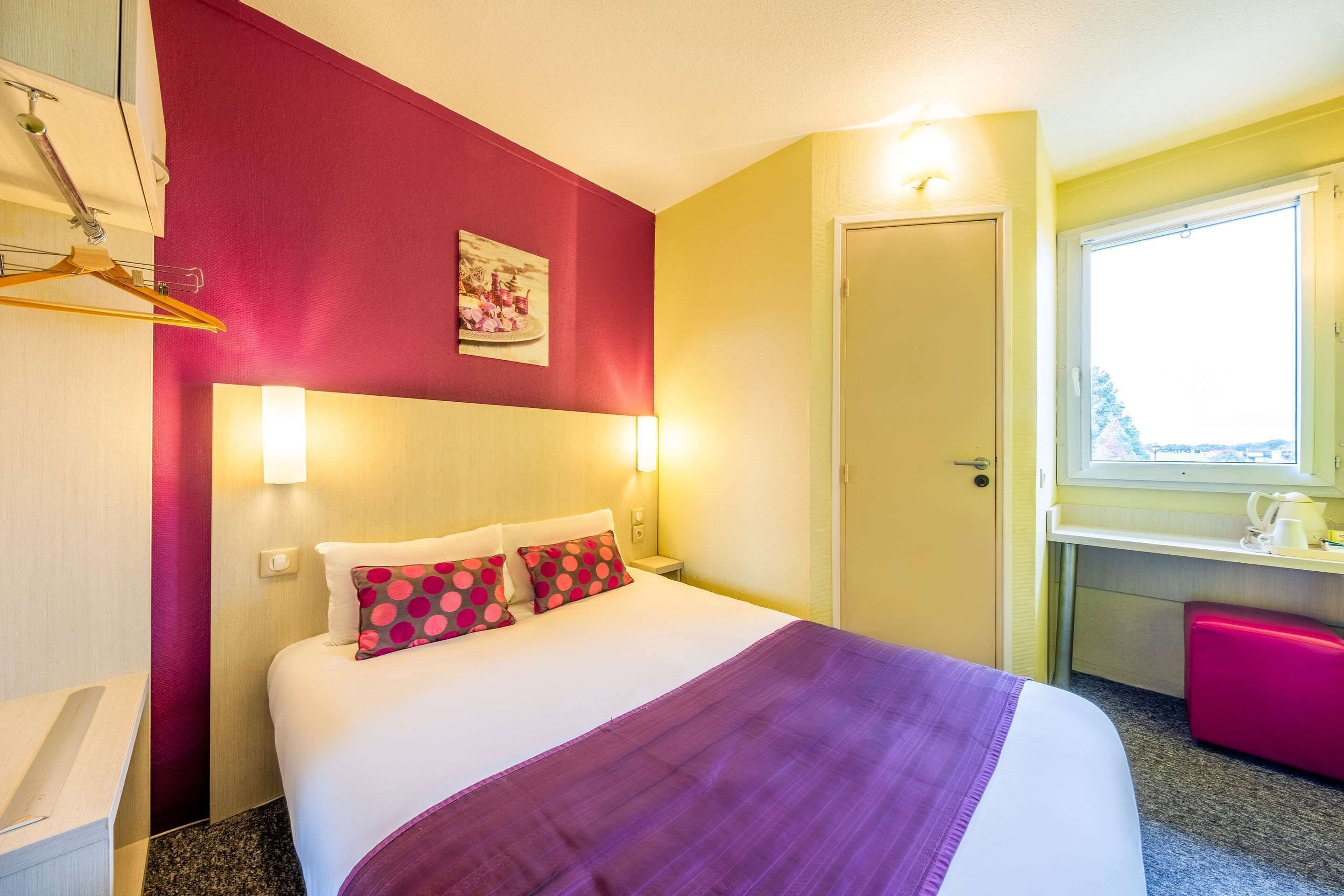 Una habitación de hotel con cama, escritorio y ventana.