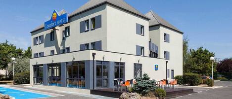 Een Comfort Hotel met twee verdiepingen, een zwembad, terras en een goed onderhouden tuin.