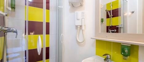 A bathroom with a glass shower enclosure, a white sink, and a mirror above it.