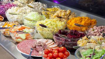A buffet with various food options including salads, rice, meats, and vegetables.