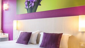 A hotel room with a large bed, two pillows, a nightstand, a lamp, and a wall-mounted light. - Comfort Hotel Orleans Olivet (Olivet)