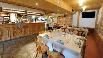 Un restaurante con interiores de madera, mesas dispuestas para comer y una zona de bar con varias botellas.