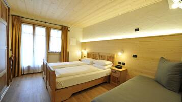 Una habitación con dos camas de madera, una mesita de noche, una lámpara y una ventana con cortinas.